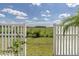 Scenic backyard view through a white fence gate, showcasing a serene and open landscape at 11895 Crestridge Loop, New Port Richey, FL 34655