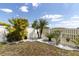 Lush backyard featuring a white fence, tropical greenery, and a peaceful seating area at 11895 Crestridge Loop, New Port Richey, FL 34655
