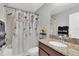 Bathroom featuring a floral shower curtain, granite countertop, and modern fixtures at 11895 Crestridge Loop, New Port Richey, FL 34655