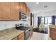Kitchen featuring granite countertops, stainless steel appliances, and wood cabinetry adjacent to a dining area at 11895 Crestridge Loop, New Port Richey, FL 34655