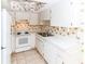 Bright kitchen featuring white appliances, cabinets, tiled floor, and neutral countertops at 1223 Queen Anne Dr # B, Palm Harbor, FL 34684