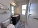 Bright bathroom with a granite countertop, dark cabinets, and decorative shelving at 12403 Coralbean Ct, New Port Richey, FL 34654