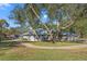 Exterior shot of a one-story home with mature trees, a long driveway and a sidewalk at 1281 Bolander Ave, Spring Hill, FL 34609