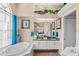 Bright bathroom with dual sinks, white cabinets, garden tub, and large window at 13045 Marbled Godwit Rd, Weeki Wachee, FL 34614