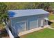 Metal garage with two roll-up doors and a single entry, set against a backdrop of green grass and trees at 13045 Marbled Godwit Rd, Weeki Wachee, FL 34614