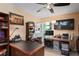 Home office with ceiling fan, built-in shelving, desk, and travertine tile flooring at 13045 Marbled Godwit Rd, Weeki Wachee, FL 34614