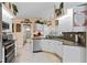 Well-lit kitchen with white cabinets, stainless steel appliances, and an adjacent bathroom at 13045 Marbled Godwit Rd, Weeki Wachee, FL 34614