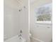 Clean bathroom featuring a white tiled shower/tub with chrome fixtures and a window at 13619 Bee Tree Ct, Hudson, FL 34669