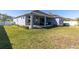 Spacious backyard featuring a covered patio, lush green grass, and manicured landscaping at 1436 Gopher Loop, Tarpon Springs, FL 34689