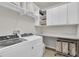 Well-organized laundry room with overhead shelving, countertop, and stainless steel laundry cart at 1436 Gopher Loop, Tarpon Springs, FL 34689