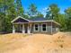 Charming single-story home featuring neutral siding, gray accents and a covered front porch in a sunny, wooded setting at 18082 Parakeet Rd, Brooksville, FL 34614