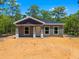 Charming single-story home featuring neutral siding, gray accents and a covered front porch in a sunny, wooded setting at 18082 Parakeet Rd, Brooksville, FL 34614
