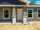 A close up view of the front porch and home exterior reveals windows and pillars under a gray gable at 18082 Parakeet Rd, Brooksville, FL 34614