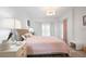 Bright bedroom with a wicker bed frame, side tables, and ample natural light from the large window at 5360 Riverwalk Preserve Dr, New Port Richey, FL 34653