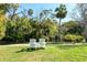Inviting white Adirondack chairs set on a lush lawn, offering a relaxing outdoor retreat by the pond at 5360 Riverwalk Preserve Dr, New Port Richey, FL 34653