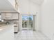 Modern kitchen with white cabinets, a breakfast bar, and a sliding glass door to the balcony at 5557 Sea Forest Dr # 318, New Port Richey, FL 34652