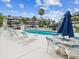 Community pool surrounded by lounge seating, tables with umbrellas, and well-maintained condominium buildings at 5557 Sea Forest Dr # 318, New Port Richey, FL 34652