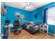Spacious, bright blue bedroom featuring a computer desk, gaming chair and a window at 5737 Wynstone Ln, Zephyrhills, FL 33541