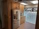 Well lit kitchen featuring stainless refrigerator and adjacent glass block window and wood-look tile floor at 5956 Seaside Dr, New Port Richey, FL 34652