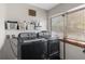 Laundry room with gray washer and dryer, natural light, shelving, and laundry supplies at 6244 Warren Ave, New Port Richey, FL 34653