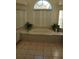 Luxurious bathroom featuring a large soaking tub surrounded by tile and lush plants at 8630 Ne Coral Creek Loop, Hudson, FL 34667