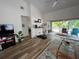 Hardwood flooring in the living room with a television, desk area, and open sliding glass doors to the porch at 9485 Hamlin Blvd # 8, Seminole, FL 33776