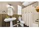 Charming bathroom features a pedestal sink, accent wall, toilet, and shower with a curtain at 10623 Marsha Dr, New Port Richey, FL 34655