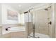 Elegant bathroom with a separate tub, glass-enclosed shower, and neutral-toned tile at 10623 Marsha Dr, New Port Richey, FL 34655
