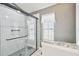 Updated shower with white tile, glass doors, and granite top vanity near a window at 11339 Alden Ct, Hudson, FL 34667