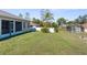 Expansive backyard view, featuring the screened patio, lush lawn, and fencing at 12450 Fish Cove Dr, Spring Hill, FL 34609