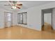 Bedroom with wood floors, mirrored closet, ceiling fan, and access to hallway at 13820 Plumosa Ave, Hudson, FL 34667