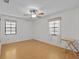 Bright bedroom with hardwood floors, ceiling fan, and natural light from two windows at 13820 Plumosa Ave, Hudson, FL 34667