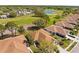 An aerial view of residential homes surrounding a golf course, a lake, and lush trees at 14471 Sterling Run, Spring Hill, FL 34609