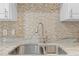 Close-up of a kitchen sink with granite countertops, mosaic backsplash, and stainless steel faucet and sink at 14471 Sterling Run, Spring Hill, FL 34609