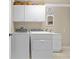 Bright laundry room with white cabinetry, modern washer/dryer, and a utility sink at 14471 Sterling Run, Spring Hill, FL 34609
