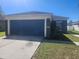 View of the home showcasing a blue garage door, concrete driveway, and manicured lawn at 14656 Wake Robin Dr, Brooksville, FL 34604