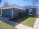 View of a home with blue garage door and well-kept yard at 14656 Wake Robin Dr, Brooksville, FL 34604