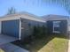 Street view of a home with a blue garage door and landscaping at 14656 Wake Robin Dr, Brooksville, FL 34604