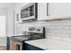 Close-up of a kitchen's stainless steel oven and microwave, subway tile backsplash at 15193 Copeland Way, Brooksville, FL 34604