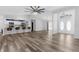 Spacious living room with wood-look flooring, featuring a ceiling fan, breakfast bar, and a view of the front double door at 15193 Copeland Way, Brooksville, FL 34604