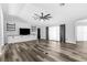Bright living room with modern wood-look flooring, ceiling fan, built-in shelves, and many windows to bring in the light at 15193 Copeland Way, Brooksville, FL 34604