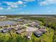 An aerial view shows a lakeside community with many homes, green lawns, and a neighborhood pond on a partly cloudy day at 15793 Midnight Dove Ct, Odessa, FL 33556