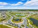 An aerial view of a community with lush landscaping, a pool, a roundabout, and well-maintained roads at 15793 Midnight Dove Ct, Odessa, FL 33556