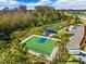 An aerial view of a fenced basketball court with green and blue surfaces and trees surrounding the court at 15793 Midnight Dove Ct, Odessa, FL 33556