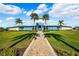 A stunning, symmetrical view of the clubhouse features a paver walkway, lush lawn, and tall palm trees at 15793 Midnight Dove Ct, Odessa, FL 33556