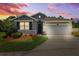 Charming single-Gathering home with a two-car garage, stone accents, lush landscaping, and a well-manicured lawn at dusk at 15793 Midnight Dove Ct, Odessa, FL 33556