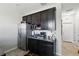Cozy kitchenette with dark cabinets, stainless steel refrigerator, and adjacent hallway at 15793 Midnight Dove Ct, Odessa, FL 33556