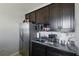 A kitchenette featuring dark cabinetry, granite countertops, and stainless steel appliances at 15793 Midnight Dove Ct, Odessa, FL 33556