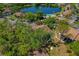 Aerial view showcasing community buildings, a shimmering lake with fountain, and a pool amidst verdant trees at 1737 Pine Ridge W Way # B-1, Palm Harbor, FL 34684