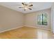 This bright and airy bedroom is well lit with a large window, ceiling fan, and smooth hardwood flooring at 1737 Pine Ridge W Way # B-1, Palm Harbor, FL 34684